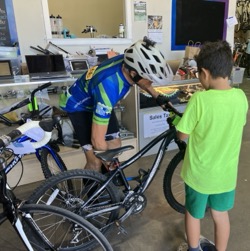 Child watches as adult adjusts his new bike