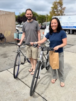 A smiling couple drops off their two used bicycles as donations