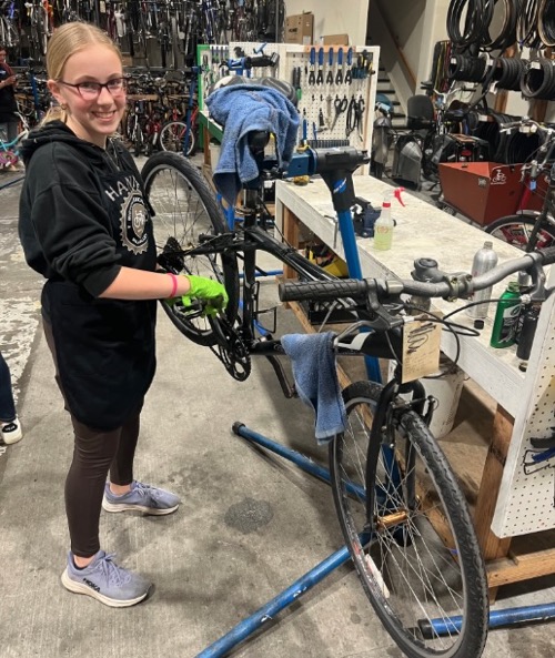 Hannah repairing a bike in the SVBE shop.  Bike on repair stand.